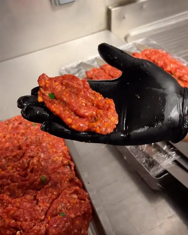 La viande de l'Adana, hachée et épicée, dans une main gantée
